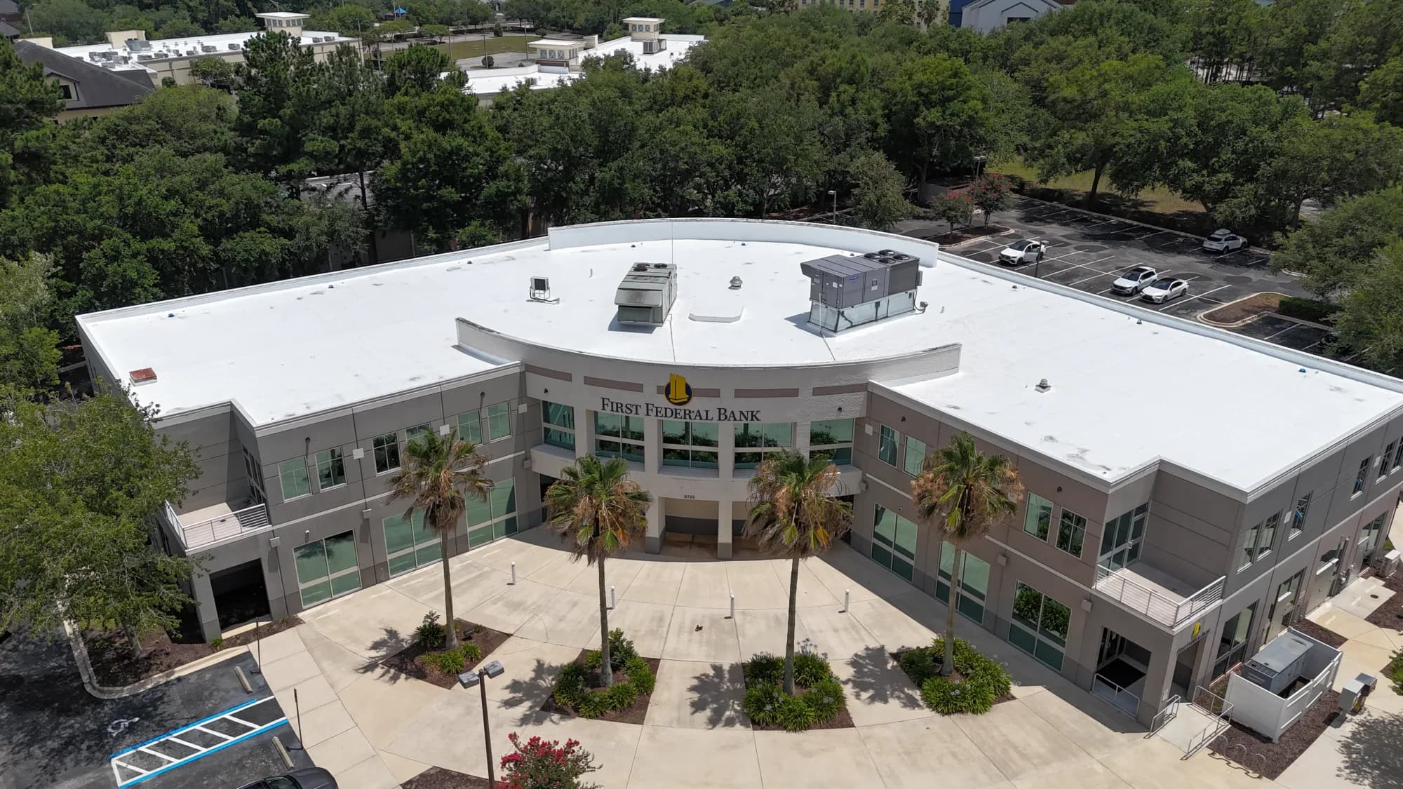 Front aerial view of a commercial building with a completed white low-slope roof