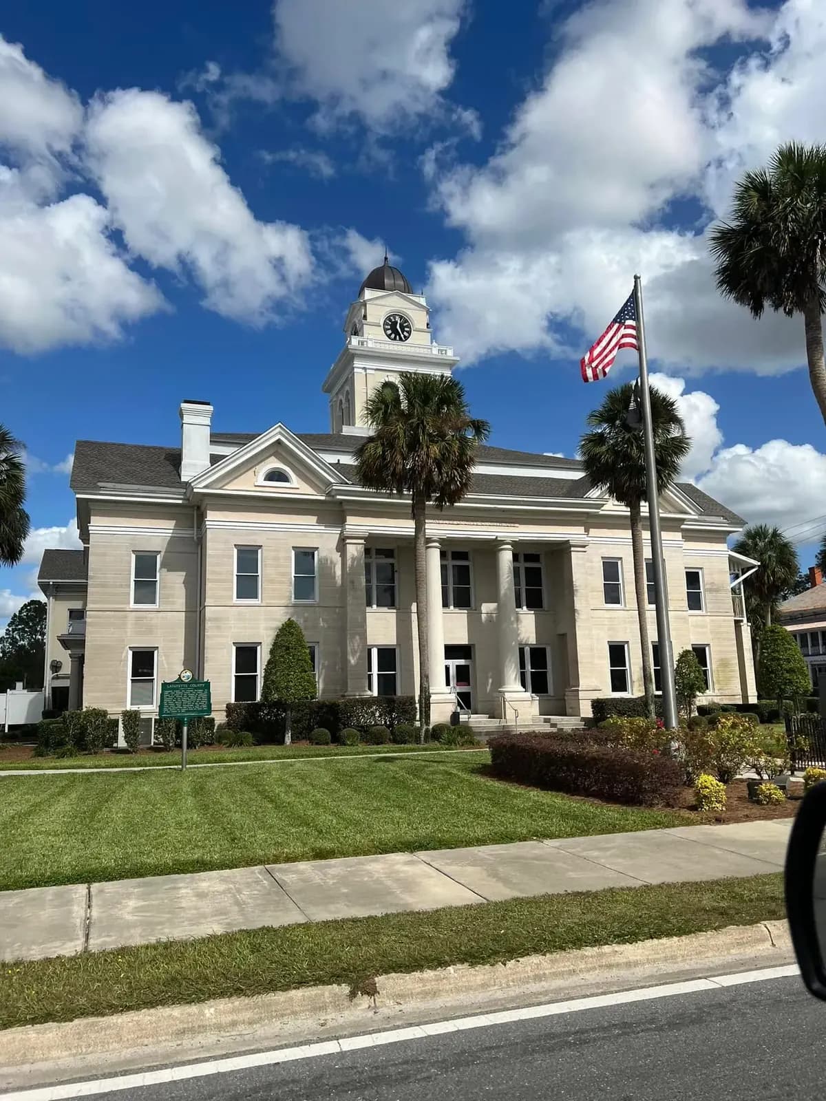 Light stone civic building with a clock tower and completed shingle roof