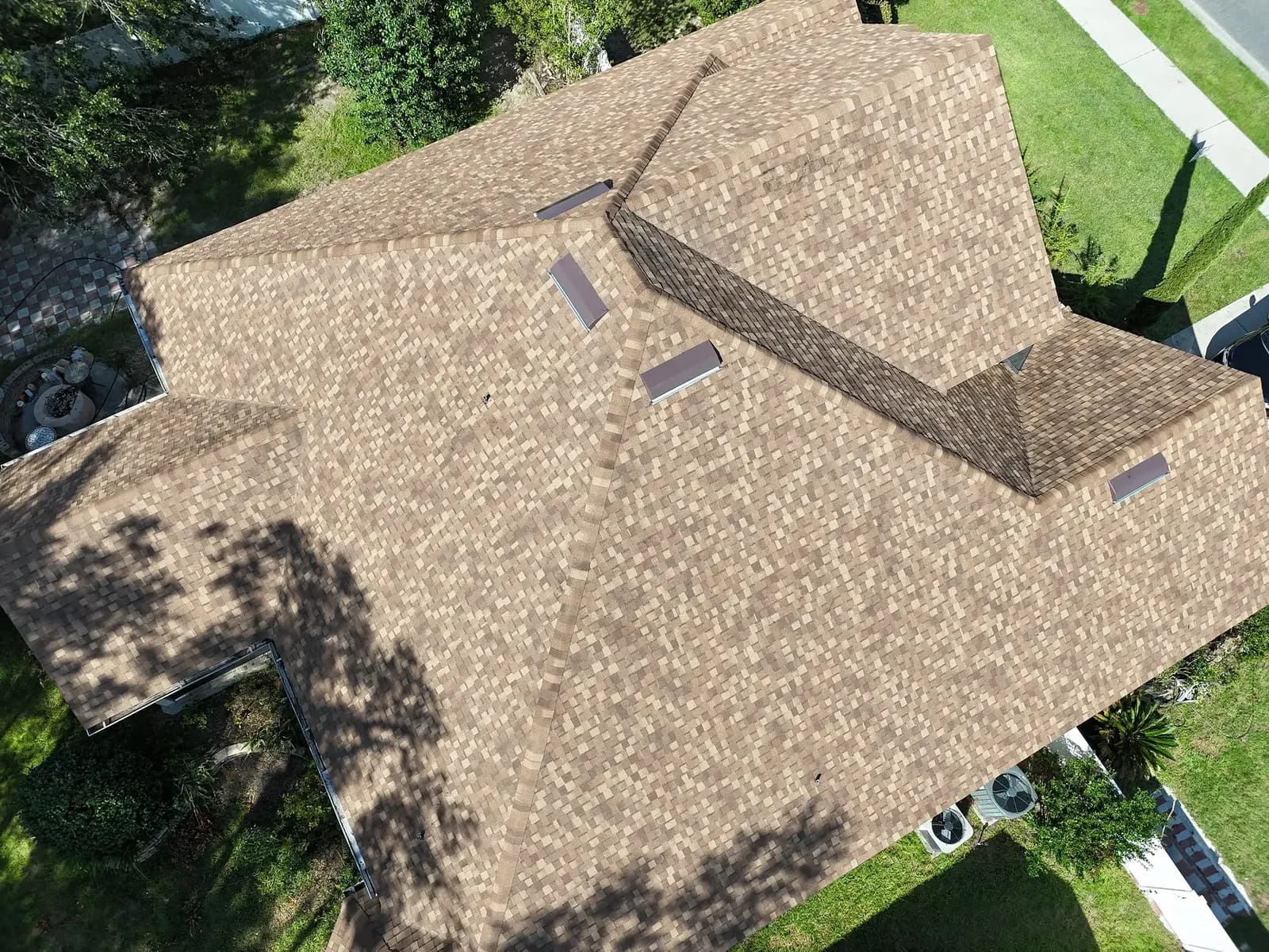 Aerial view of a tan architectural shingle roof with hips and gables