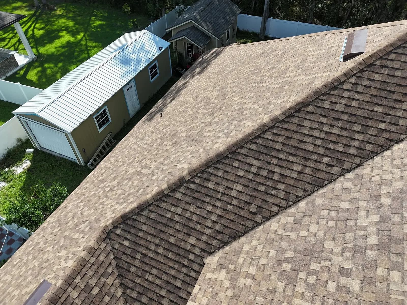 Close aerial view of intersecting brown architectural shingle roof planes