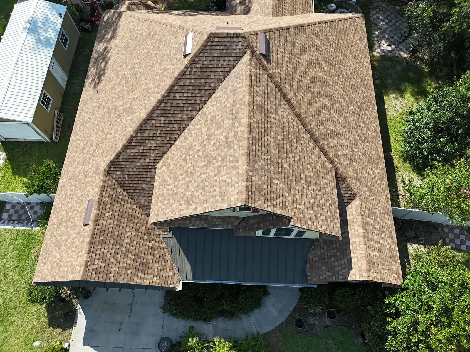 Aerial view of a completed tan hip-and-gable shingle roof