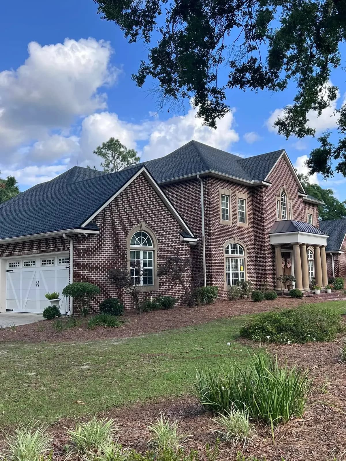 Brick two-story home with a dark architectural shingle roof