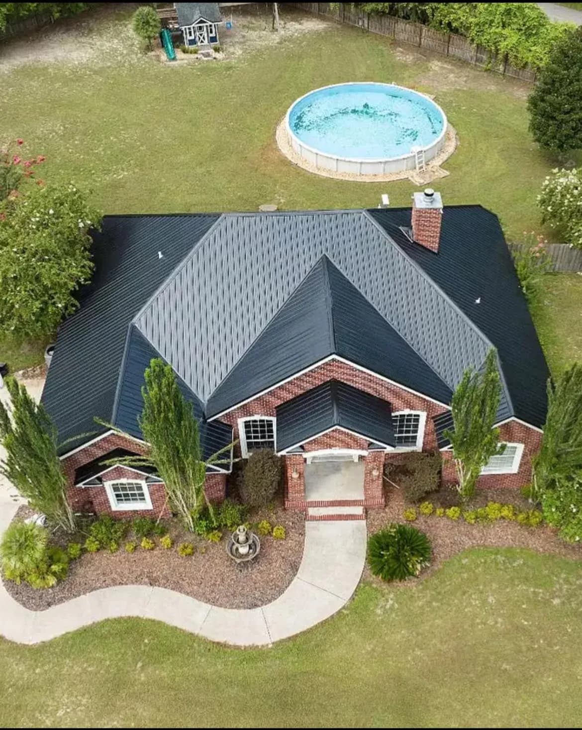 Brick home with a completed dark shingle roof viewed from above