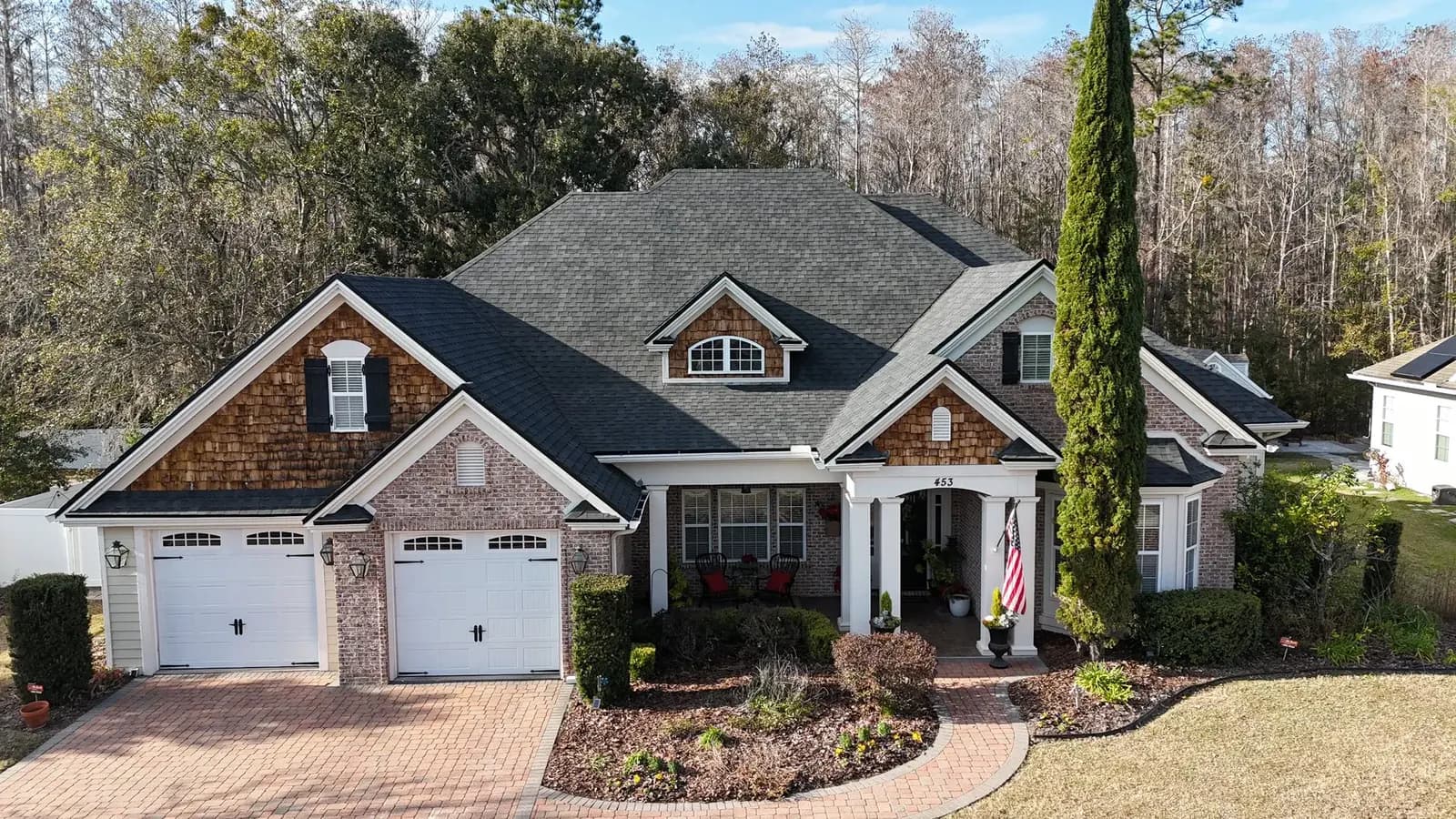 White and brick home with a completed gray architectural shingle roof