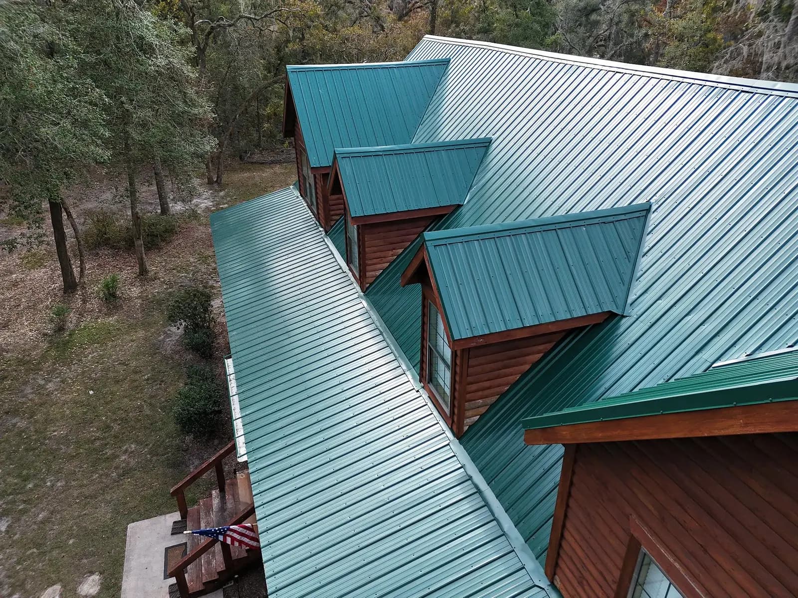 Aerial detail of teal standing-seam metal roofing on a wood cabin