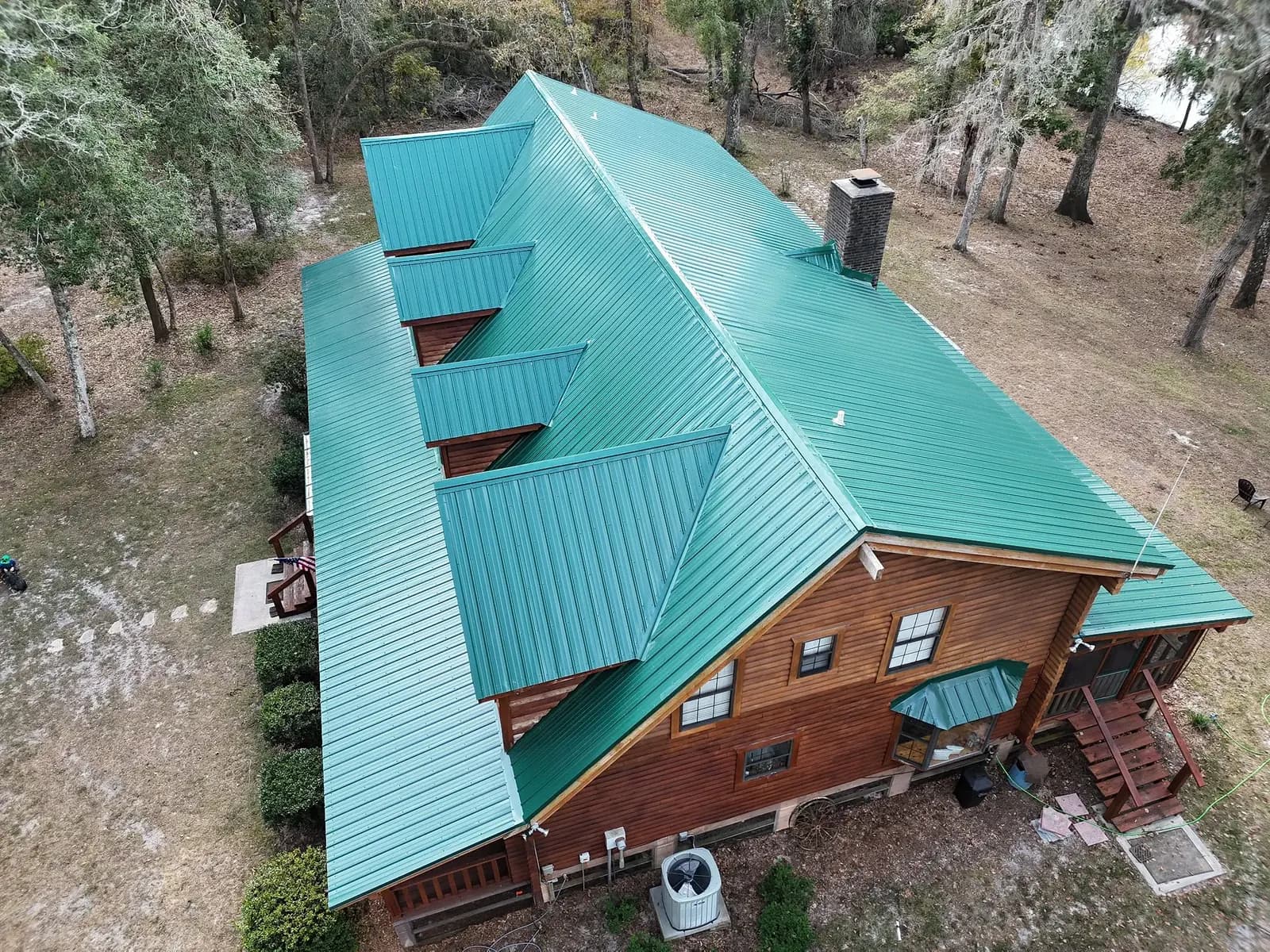 Upper aerial view of a teal metal roof with multiple dormers