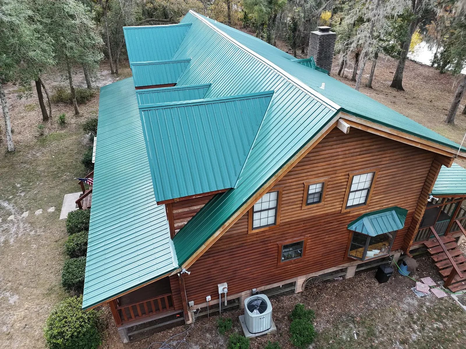 Side aerial view of teal metal roofing on a large log home