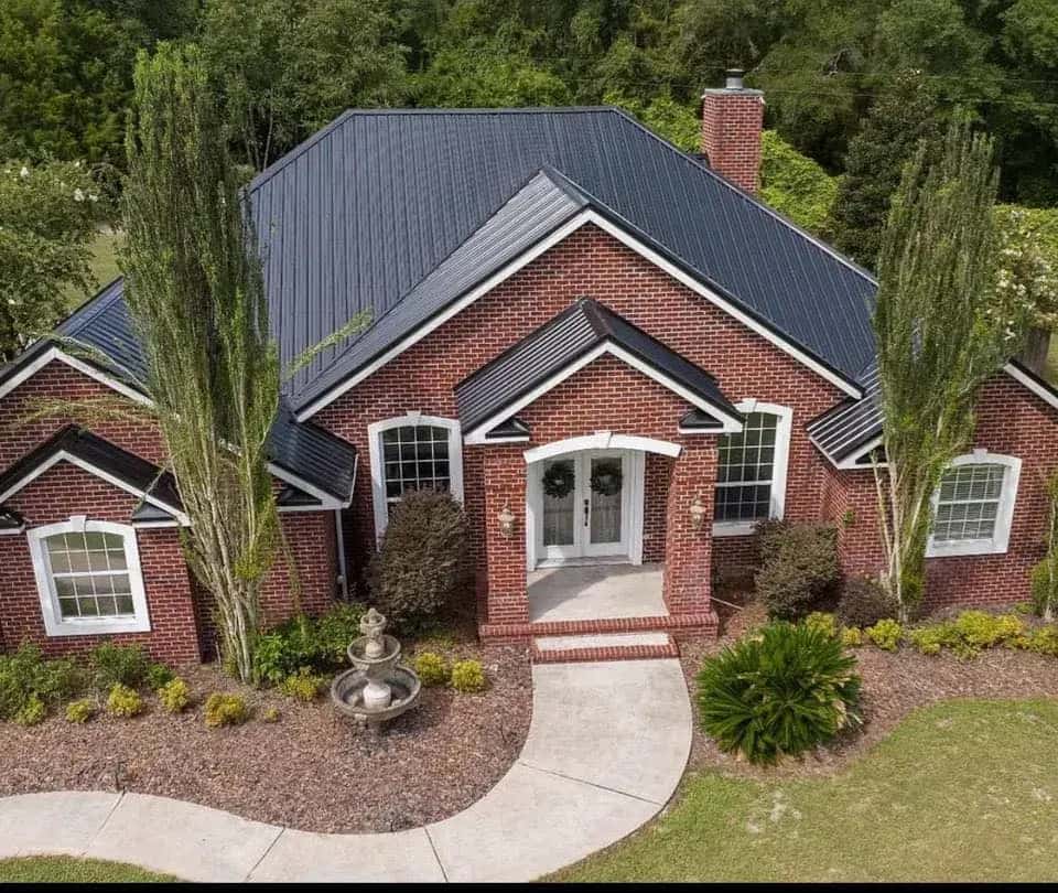 Brick home with a completed charcoal standing-seam metal roof